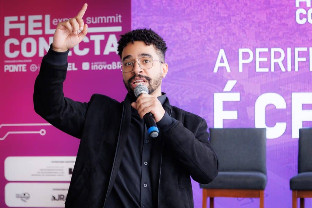 Fotografia de palestrante com microfone durante evento corporativo